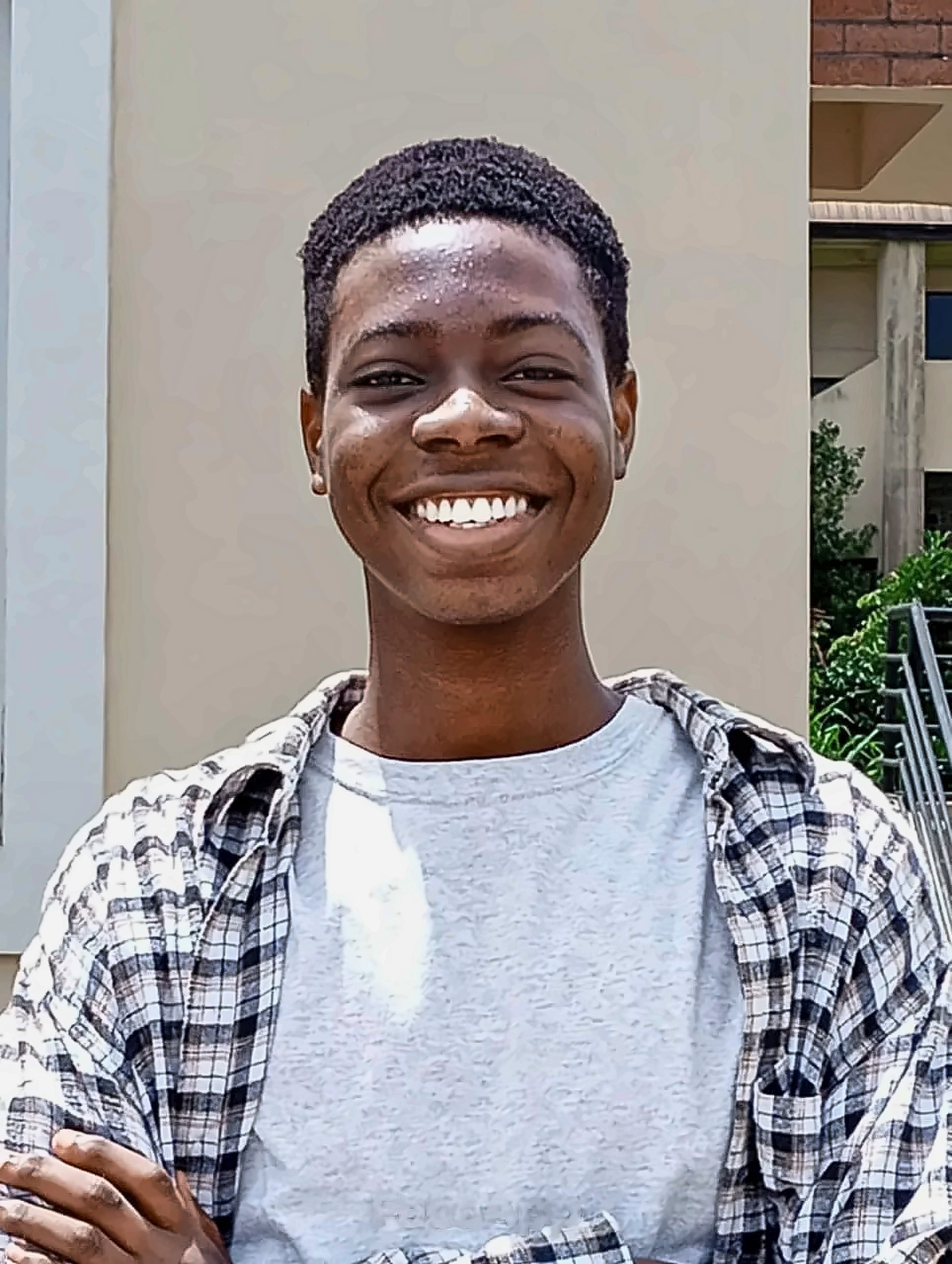 Michael Dunsin smiling, wearing a grey T-shirt under an open checked shirt